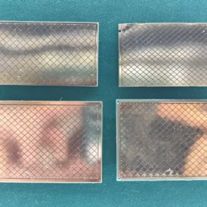 Four gold-plated ceramic substrates with grid pattern on green background