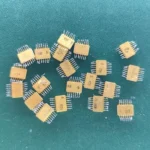 Twenty USSR ceramic ICs with gold pins scattered on a green background.