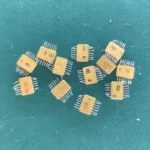 Twelve USSR ceramic ICs with gold tops and gold-plated pins scattered on a green background.