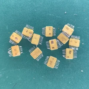 Twelve USSR ceramic ICs with gold tops and gold-plated pins scattered on a green background.